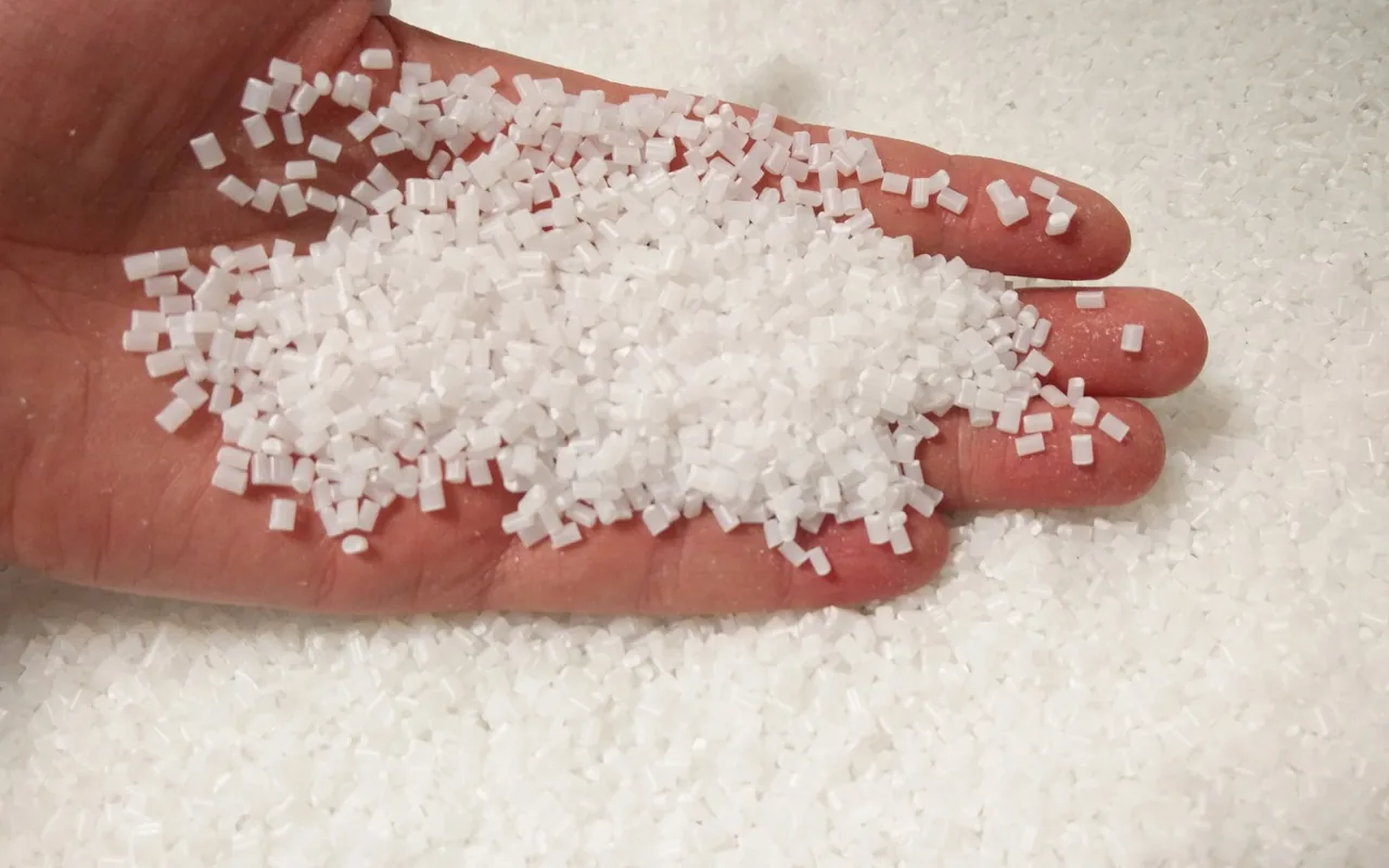 White ABS polymer granules held in a hand.